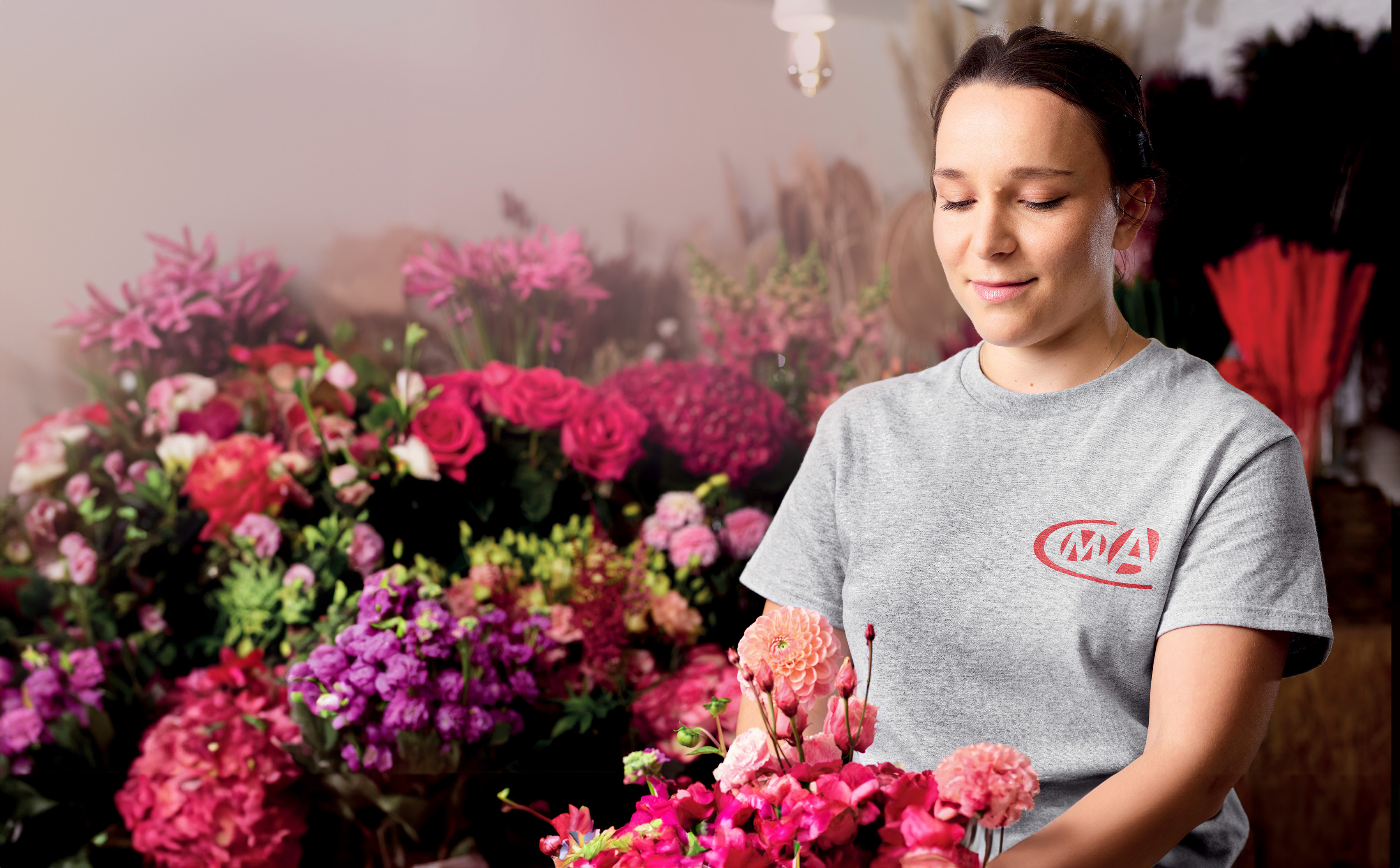 Artisane fleuriste portant un tee-shirt CMA en train de faire un bouquet 