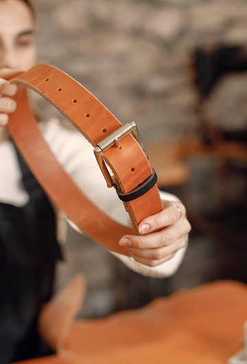 Artisane présentant une ceinture en cuir